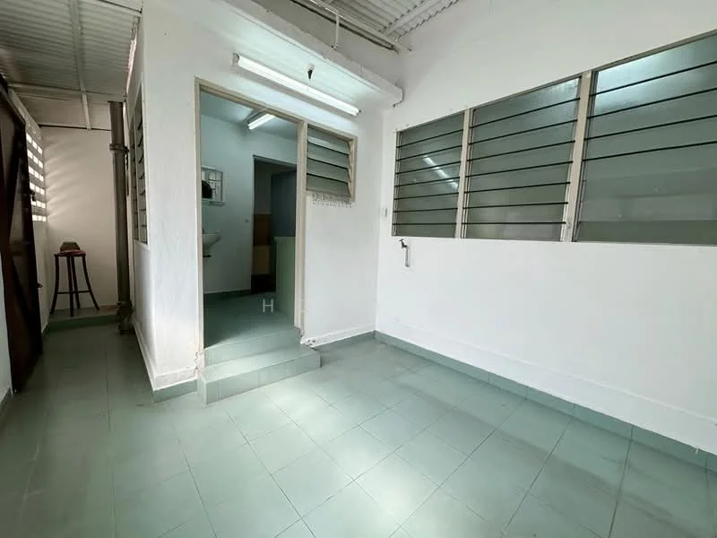 Room features: white painted walls, green tiled flooring, sliding windows with metal grilles, fluorescent ceiling light, step-up entrance, open layout, no visible furniture, natural light from windows; style: minimalist.