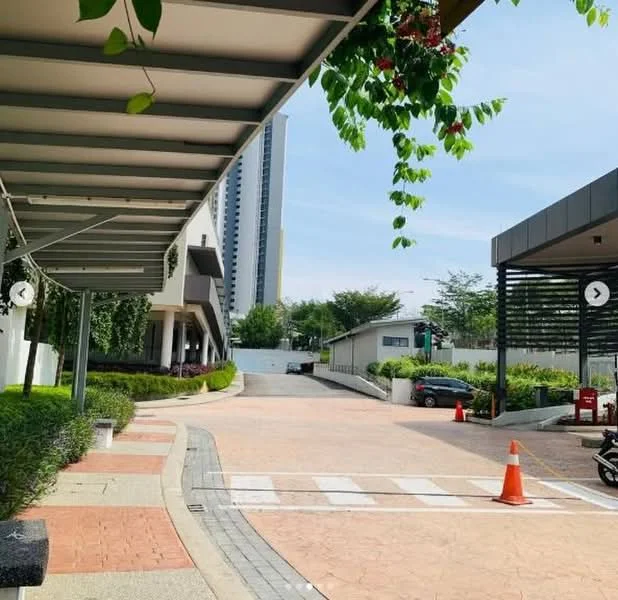 Exterior type: low-rise apartment block; features: paved driveway, landscaped greenery, overhead canopy with vines, traffic cones, surrounding trees, modern architectural design, adjacent building with glass facade, clear blue sky; style: modern.