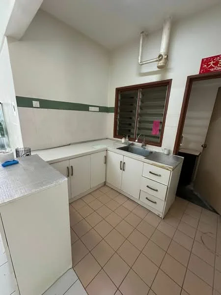 Kitchen features: L-shaped countertop, white cabinetry, stainless-steel sink, chrome faucet, tile backsplash, cream tiled flooring, window with horizontal slats, wall-mounted pipes, green accent stripe on wall, door leading to another room.