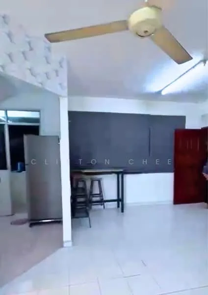 Room features: white painted walls, tile flooring, 5-blade ceiling fan, large window, bar table with stools, refrigerator, grey wall panel, light fixture.