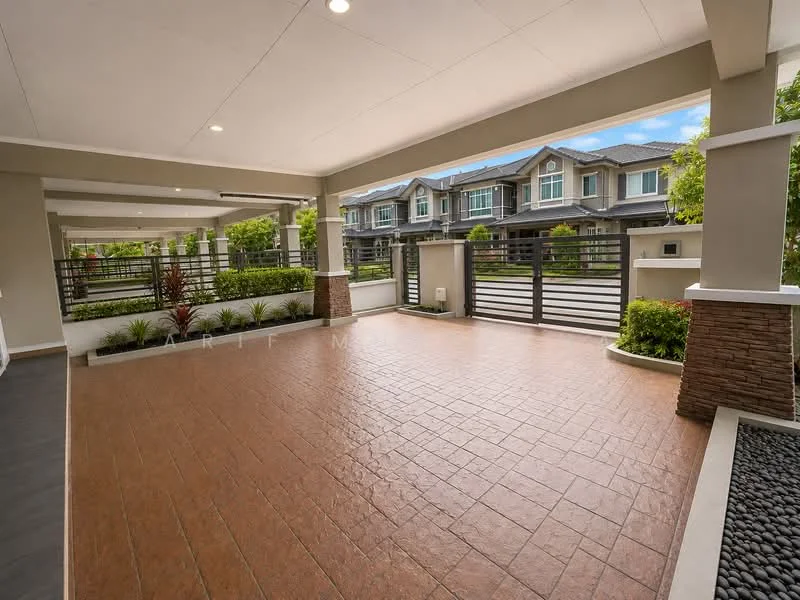 Exterior type: linked terrace house; features: paved driveway, manicured landscaping, stone cladding on columns, fenced perimeter, outdoor lighting, covered porch area, garden beds with plants, sliding gate entrance, concrete walls, two-storey residential buildings in background; style: modern.
