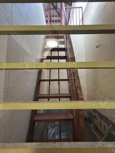 Room features: metal staircase, red painted railing, white tiled walls, concrete flooring, natural light from upper level, open space, no visible decor, industrial style; style: industrial.