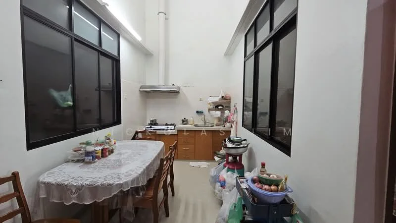 Kitchen features: white walls, tile flooring, wood cabinetry, stainless-steel range hood, built-in stove, kitchen table with lace tablecloth, wooden dining chairs, large windows, sink, various kitchen appliances, countertop cluttered with utensils and food items.