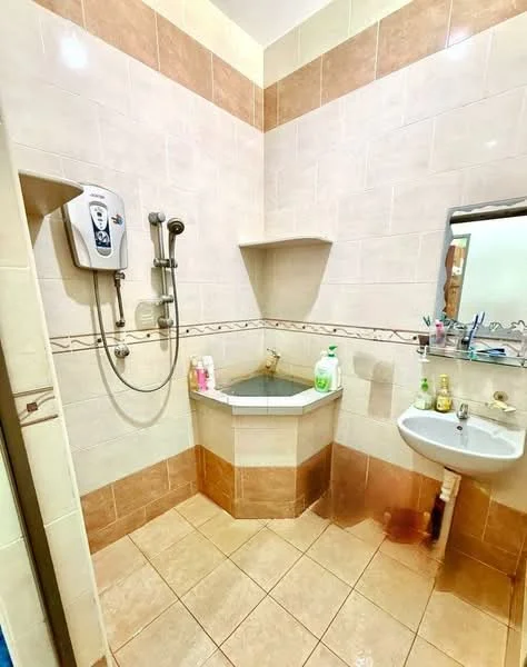 Bathroom features: shower with handheld showerhead, wall-mounted shower mixer, corner bathtub, white sink with pedestal, mirror above sink, cream tiled walls, brown tiled accents, ceramic tile flooring, shelf above bathtub, various toiletries on shelf.