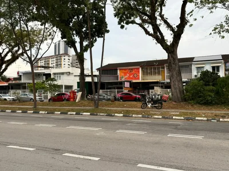Exterior type: shophouse; features: two-storey building, red brick facade, balconies on the second floor, large signage on the front, parking spaces visible, trees lining the street, street view with road, urban setting, adjacent to high-rise buildings; style: traditional.