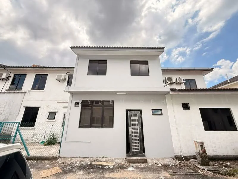 Exterior type: semi-detached house; features: white painted facade, flat roof, two-storey building, multiple windows, air conditioning units visible, metal gate at entrance, concrete pathway, surrounding fencing, manicured lawn area, cloudy sky in background; style: modern.