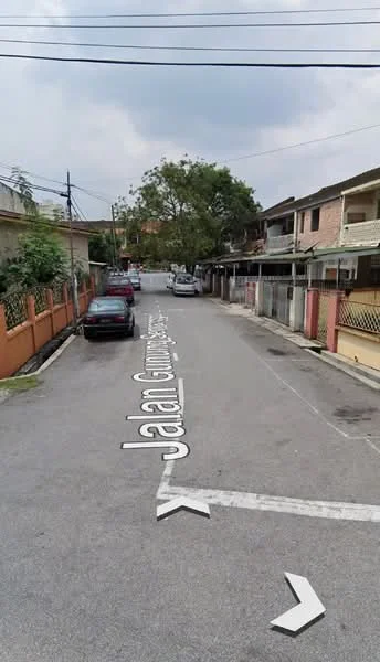 Exterior type: linked terrace house; features: residential street view, paved road, street signage, utility poles, trees along the street, fenced properties, parked cars, two-storey houses, front yards with low walls; style: traditional.