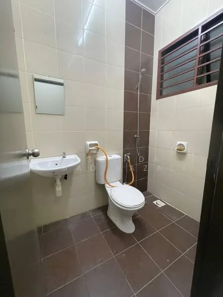 Bathroom features: white ceramic toilet, chrome basin mixer faucet, small wall-mounted sink, mirror above sink, shower with handheld showerhead, brown tiled flooring, cream tiled walls, window with horizontal bars, toilet paper holder.