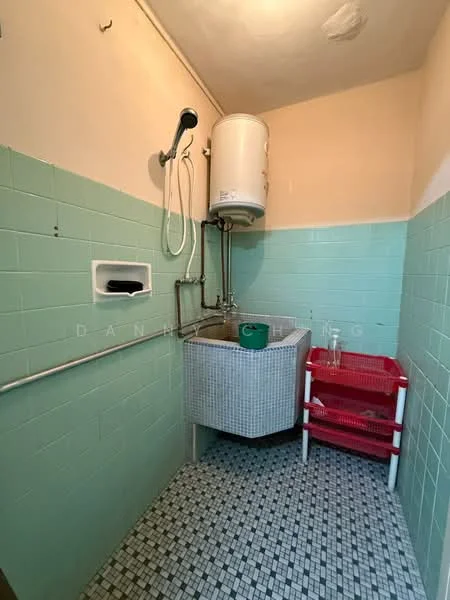 Laundry features: green tiled walls, white tiled flooring, washing sink with faucet, water heater mounted on wall, red plastic storage cart, wall-mounted drying rack, window for natural light, pipework visible.