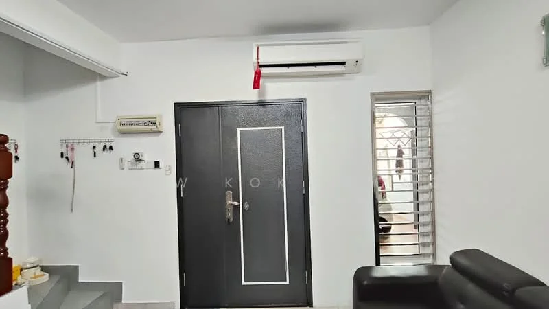 Room features: black front door, white painted walls, 1 wall-mounted split AC, window with security bars, light grey flooring, key hooks on wall, staircase visible, black leather sofa; style: modern.