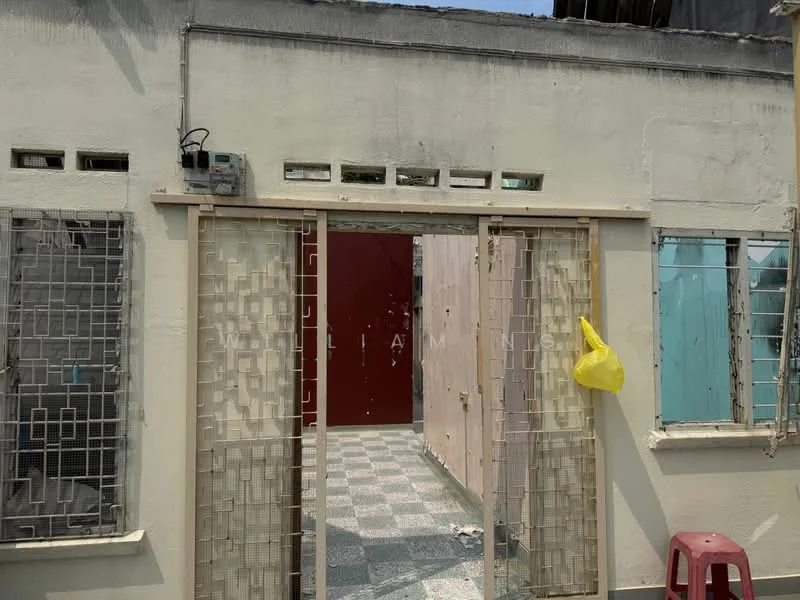 Exterior features: white painted facade, metal grilles on windows, open doorway, checkered flooring, yellow plastic bag hanging, exposed wall with no finish, partially visible interior wall, roof overhang.