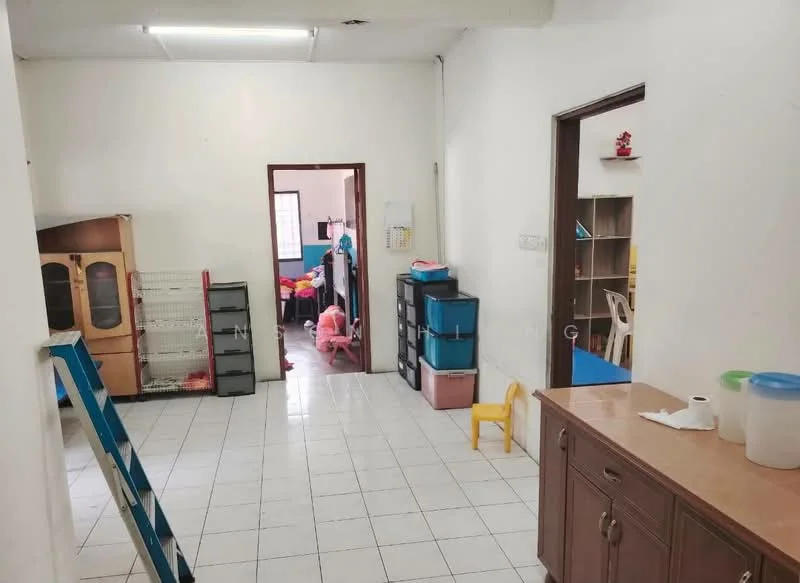 Room features: white painted walls, white tiled flooring, ceiling lights, wooden cabinet, plastic storage bins, small yellow chair, open doorway, shelving unit, ladder, furniture in background.