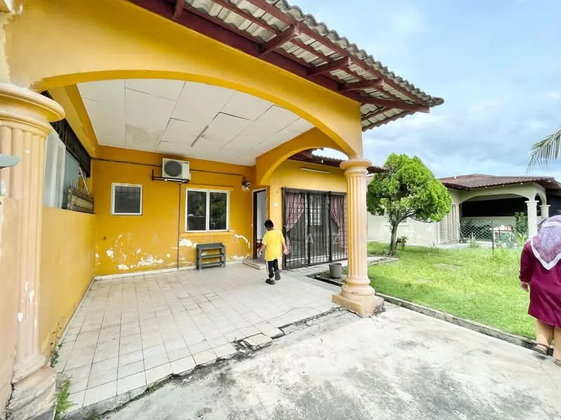 Exterior type: detached bungalow; features: yellow painted facade, flat roof with overhang, columns at entrance, tiled flooring, wall-mounted split AC unit, sliding glass door, manicured lawn, fenced yard, adjacent to another building; style: traditional.