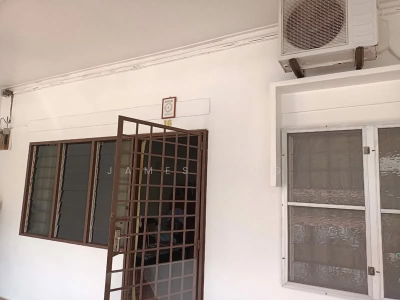 Room features: white painted walls, window with metal grille, air conditioning unit mounted on wall, wooden door with metal grille, glass window with white frame.