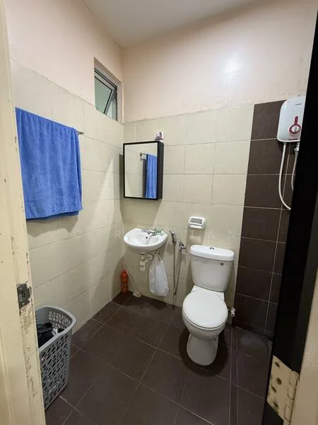 Bathroom features: white tiled walls, brown tiled walls, dark brown floor tiles, single-sink vanity, mirror, one-piece toilet, shower head, water heater, blue towel, laundry basket.