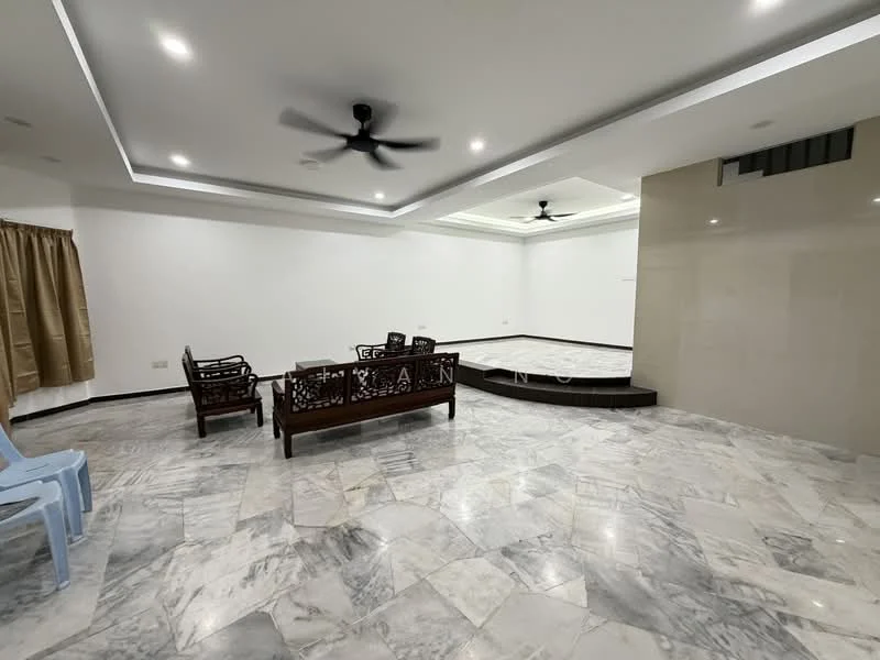 Living features: marble flooring, white painted walls, tray ceiling with recessed lighting, 2-blade ceiling fan, wooden sofa set with intricate carvings, wooden coffee table, large empty wall space, step-up platform area; style: modern.