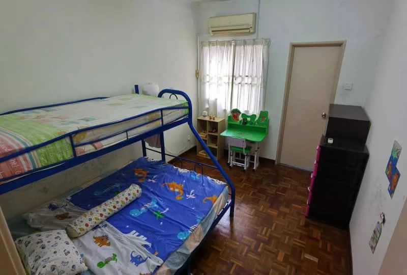 Bedroom features: bunk bed with blue metal frame, single bed with colorful bedding, wooden parquet flooring, white painted walls, window with sheer curtains, air conditioning unit, small study table with green chairs, chest of drawers in dark wood, decorative wall art, colorful bedspread with animal prints.