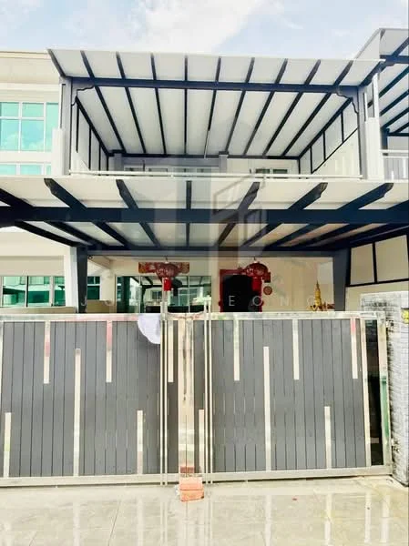 Exterior type: detached bungalow; features: flat roof with exposed beams, grey painted facade, large windows, double main entrance gate, manicured lawn, paved driveway, outdoor terrace, decorative elements at entrance; style: modern.