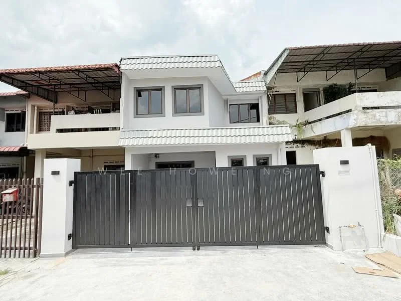 Exterior type: semi-detached house; features: grey painted facade, pitched tile roof, double-storey structure, black metal gate, concrete driveway, surrounded by greenery, balcony on upper floor, front porch area; style: modern.