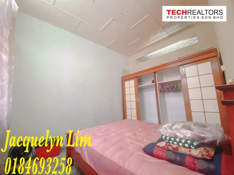 Bedroom features: light blue painted walls, white ceiling, wooden wardrobe with sliding doors, pink bedspread, stack of folded blankets, window with natural light, laminate flooring, decorative wall paneling.