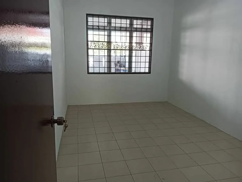 Room features: white painted walls, tile flooring, square grid window with metal grille, single door, empty room.