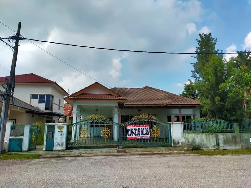 Exterior type: detached bungalow; features: gated entrance with decorative metalwork, single-storey structure, pitched tile roof, cream painted facade, manicured lawn, surrounded by greenery, driveway with interlocking pavers, visible for sale sign, front porch, mature trees in the vicinity; style: modern.