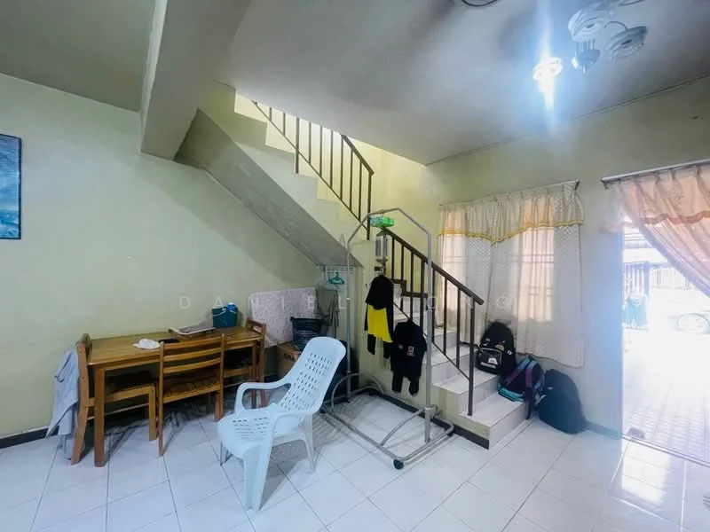 Room features: white painted walls, tile flooring, staircase with metal railing, ceiling lights, curtains on window, dining table with 6 chairs, plastic chair, clothes hanging on rack, back door leading outside, bags on the floor.