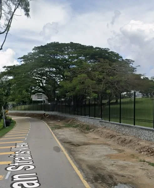 Exterior features: tree with large canopy, fenced perimeter, paved road, grass field, curved road, road markings.