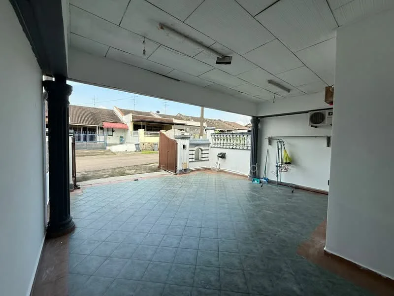 Room features: white painted walls, grey tiled flooring, exposed ceiling with fluorescent lights, wall-mounted air conditioning unit, open space layout, large opening to outdoor area, metal support columns, utility hooks on wall.