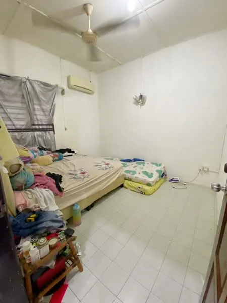 Bedroom features: queen-size bed with floral bedding, single mattress on the floor, white painted walls, tiled flooring, ceiling fan, wall-mounted air conditioning unit, curtains on window, clothes on the floor, small bedside table, decorative wall light.