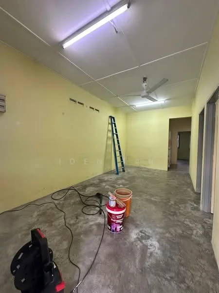 Room features: yellow painted walls, concrete flooring, exposed ceiling, ceiling fan, ladder, paint buckets, extension cord, electrical panel.
