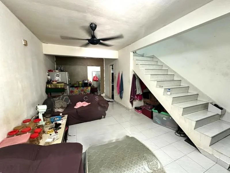 Living features: white painted walls, tiled flooring, 5-blade ceiling fan, sofa in brown fabric, coffee table, staircase with grey steps, storage boxes, sewing machine on table, decorative wall hangings, curtains in various colors.