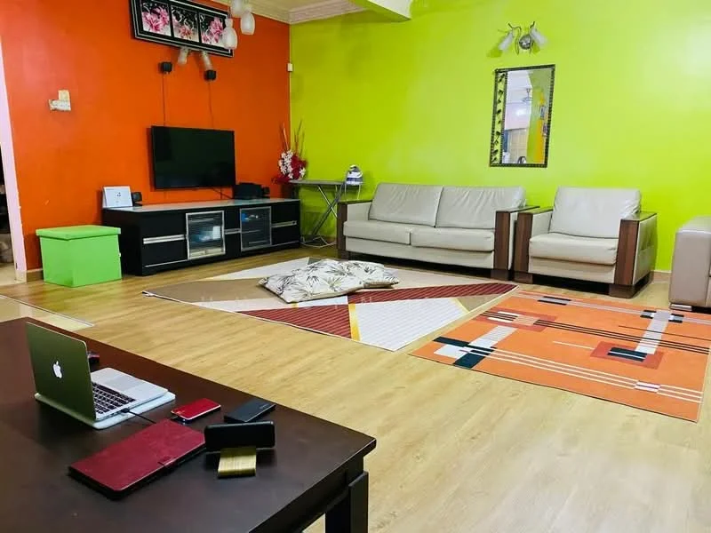 Living features: orange painted wall, green painted wall, wooden flooring, 2 beige leather sofas, coffee table, TV console with glass doors, wall-mounted TV, decorative wall art, area rug with geometric pattern, floor lamp, mirror, decorative plants; style: modern.