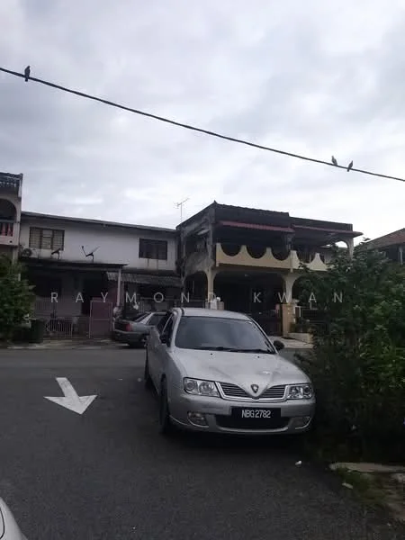 Exterior type: linked terrace house; features: two-storey building, cream painted facade, balcony with decorative railing, front porch area, manicured shrubs, asphalt driveway, grey sedan parked in front, overcast sky; style: traditional.