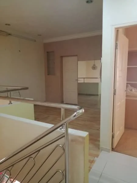 Room features: light-colored painted walls, wooden flooring, white ceiling, doorway leading to another room, metal railing, built-in cabinetry visible in the background, recessed lighting, open space layout; style: modern.
