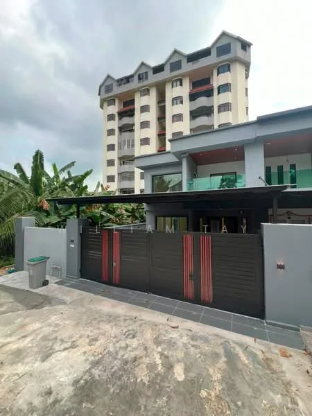 Exterior type: low-rise apartment block; features: black metal gate, grey exterior walls, glass balcony railings, multiple storeys, flat roof, surrounded by greenery, paved driveway, large windows, overhanging eaves, concrete facade; style: modern.