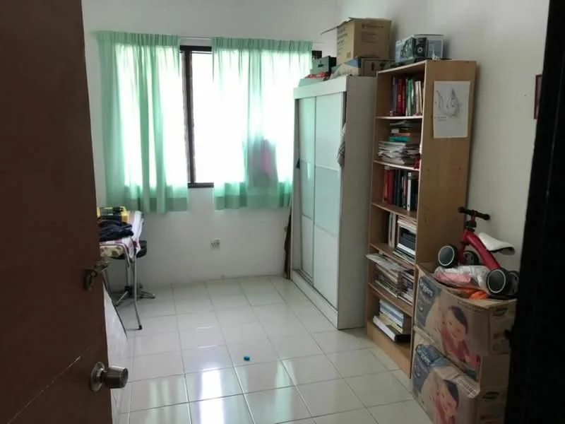 Room features: white painted walls, glossy tile flooring, green sheer curtains, single window, built-in wardrobe with sliding doors, bookshelf with books, desk with chair, cardboard boxes, toy tricycle.