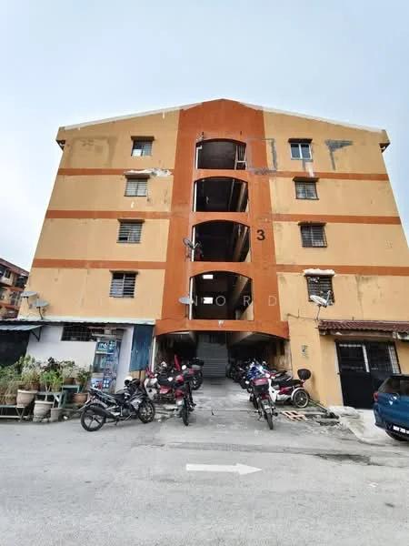 Exterior type: low-rise apartment block; features: orange and beige painted facade, three-storey building, exposed concrete, balconies with metal railings, parking area for motorcycles, entrance with number 3, surrounding greenery, asphalt driveway; style: modern.
