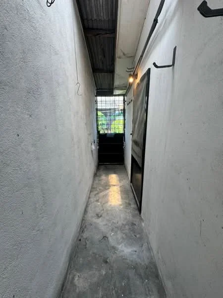 Room features: white painted walls, concrete flooring, metal roof, overhead lighting, window with security bars, hooks on walls.