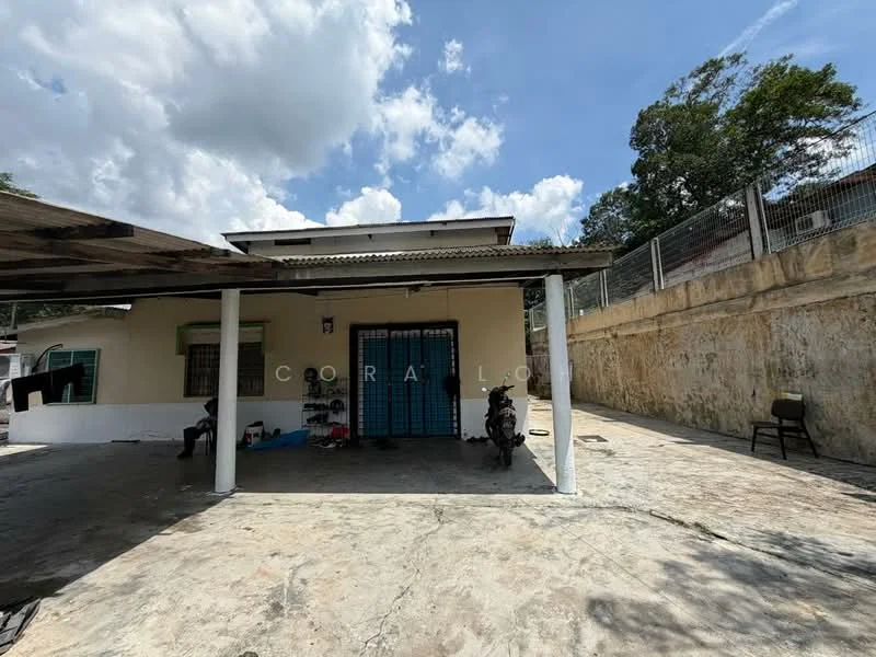 Exterior type: detached bungalow; features: single-storey, concrete flooring, covered porch area, blue sliding doors, exposed concrete walls, surrounded by greenery, parking space visible, fenced perimeter, outdoor seating area; style: modern.