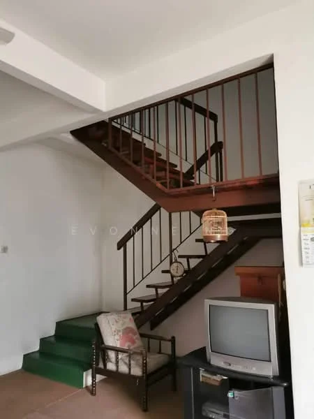 Room features: wooden staircase, green carpeted steps, white painted walls, wooden railing, television, wooden cabinet, decorative birdcage, armchair with floral upholstery; style: traditional.