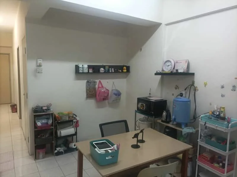 Room features: white painted walls, tile flooring, table with four legs, black shelving unit on wall, various storage containers, kettle, blue water dispenser, microwave, wall clock, decorative wall stickers, multiple bags hanging on wall, small cart for storage; style: minimalist.