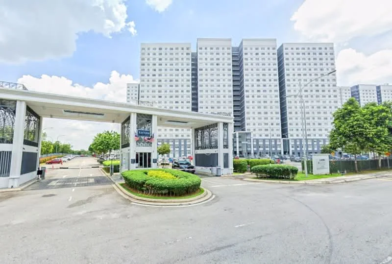 Exterior type: high-rise condominium; features: modern facade with grey and white panels, guard house at entrance, manicured landscaping with shrubs, open-air parking lot, surrounded by mature greenery, multiple storeys visible, driveway with interlocking pavers; style: modern.