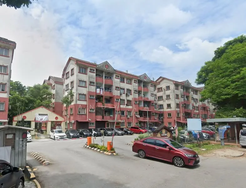 Exterior type: low-rise apartment block; features: red and cream painted facade, 3-storey building, balconies on each unit, landscaped greenery surrounding the building, parking lot with multiple cars, entrance with signage, paved driveway, trees providing shade; style: modern.