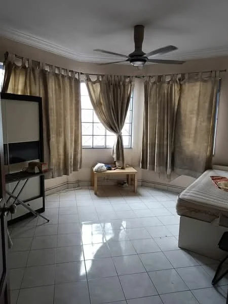 Bedroom features: white painted walls, tiled flooring, 5-blade ceiling fan, floor-to-ceiling windows, sheer curtains, wooden bedside table, bed with mattress, folding chair, ironing board.