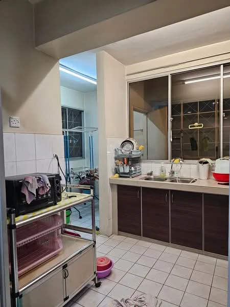 Kitchen features: white tiled walls, light grey cabinetry, stainless-steel sink, chrome faucet, countertop with yellow edge, microwave, dish rack, floor tiles in light grey, window with metal grille, open shelving, kitchen cart, washing area, clothes drying rack.