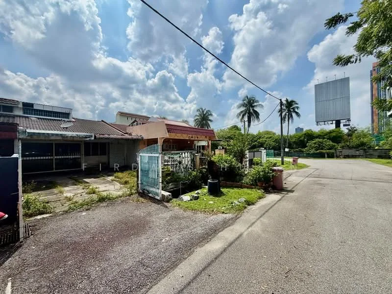 Exterior type: detached bungalow; features: single-storey building, manicured lawn, paved driveway, surrounded by greenery, palm trees, billboard in background, open space, front yard with plants; style: traditional.