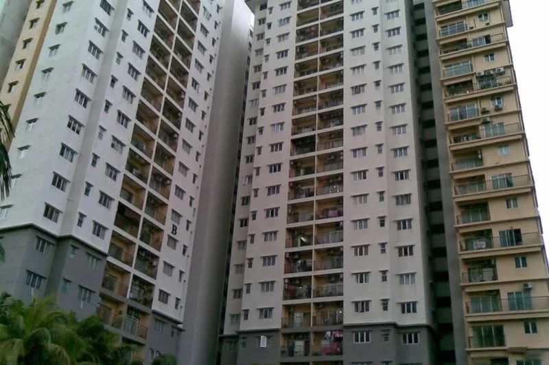 Exterior type: high-rise condominium; features: grey painted facade, cream painted facade, balconies with sliding glass doors, multiple storeys, visible air conditioning units, windows with white frames, surrounded by greenery; style: modern.