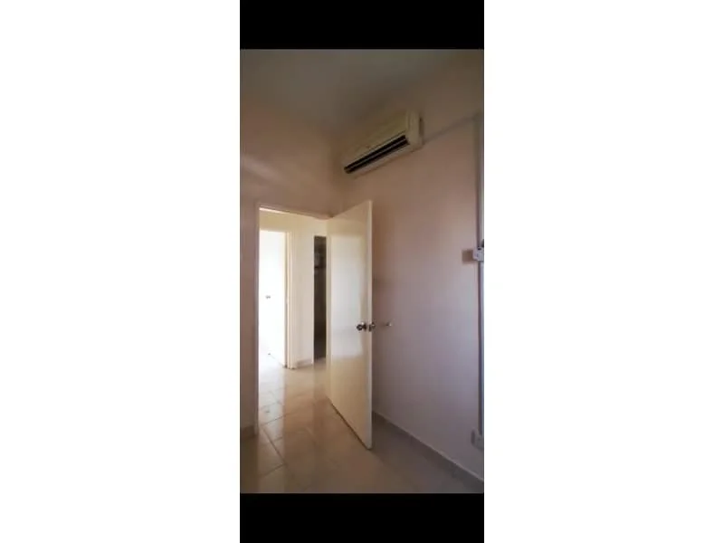 Room features: white painted walls, tile flooring, 1 wall-mounted split AC, door with doorknob, light switch, visible door frame, neutral color scheme.