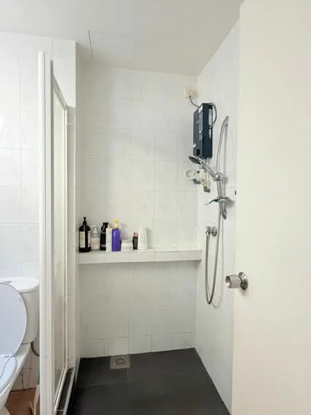 Bathroom features: white tiled walls, grey tile flooring, walk-in shower with glass enclosure, chrome shower head, wall-mounted shower controls, toilet, shelf with toiletries, drain in floor; style: modern.